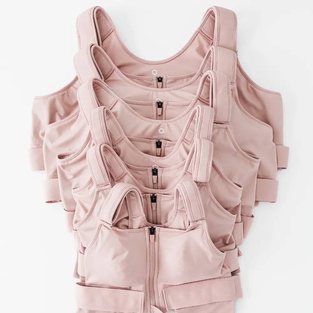 Stack of pink resilience bras in different sizes on a white background