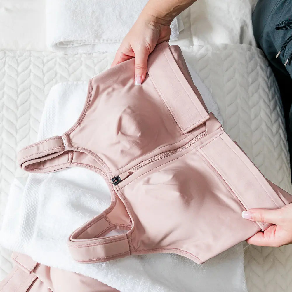A woman's pink resilience bra held by hands on a white background